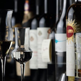 ワインボトルと赤ワイン、キャンドルが並ぶ夜のレストランの様子